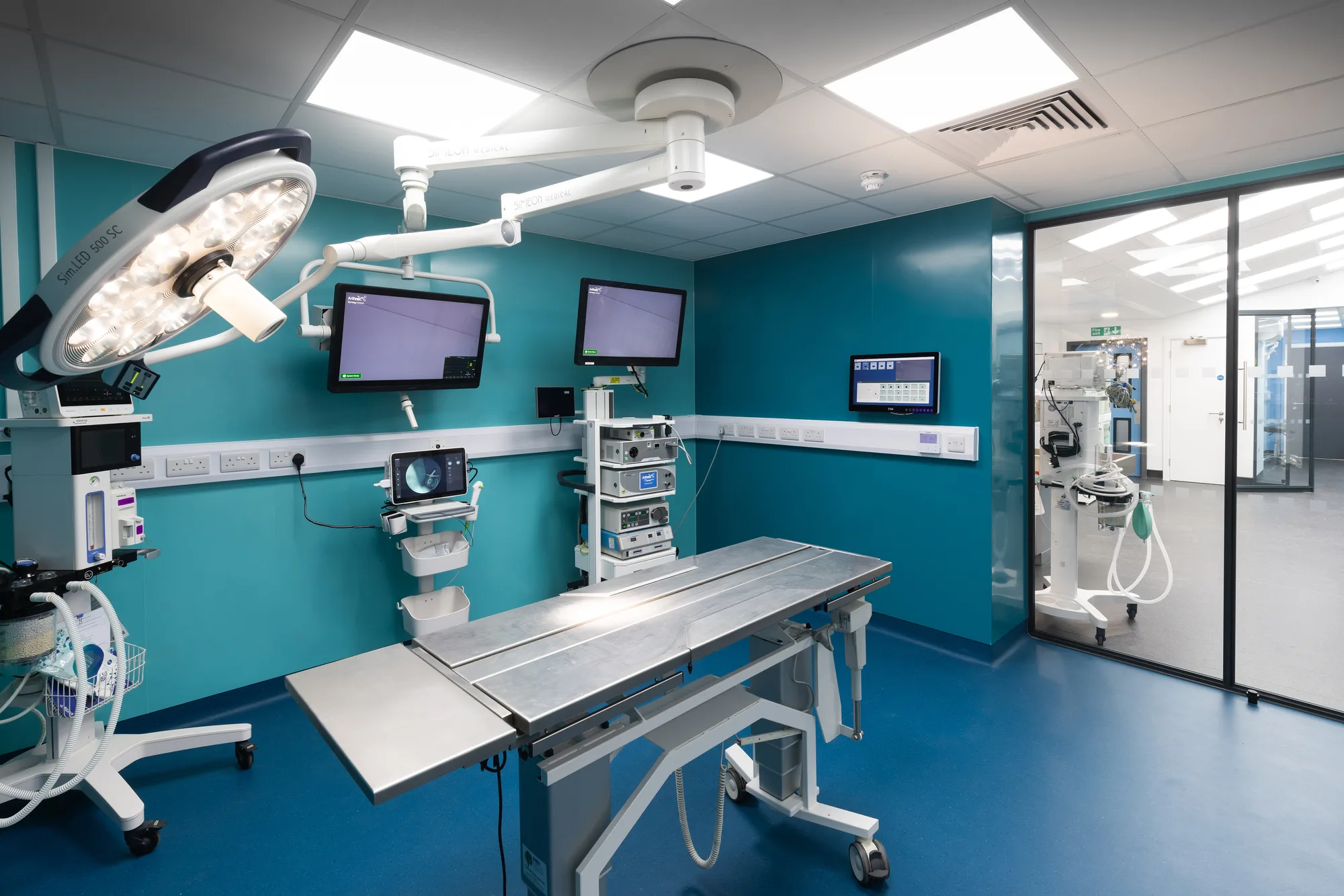 Operating theatre at Vetemis Referrals, Brownhills, with ceiling-mounted surgical light, wall monitors and glazed doors to the prep area